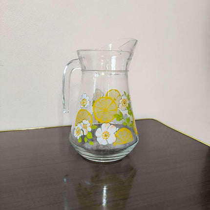 Glazen karaf met citroenen en witte bloemen